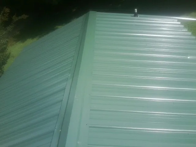 New green metal panels meeting at the ridge of a roof — Flat Roof Repair work by our crew in Vance