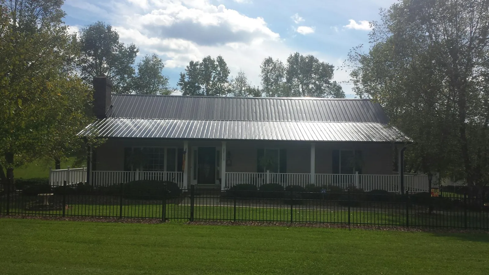 Gray metal roof on a brick ranch with a full width front porch — Gutter Guard Installation work by our crew in Vance