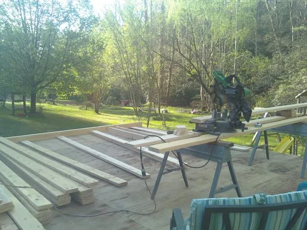 Miter saw and framing lumber on a deck under construction in Vance